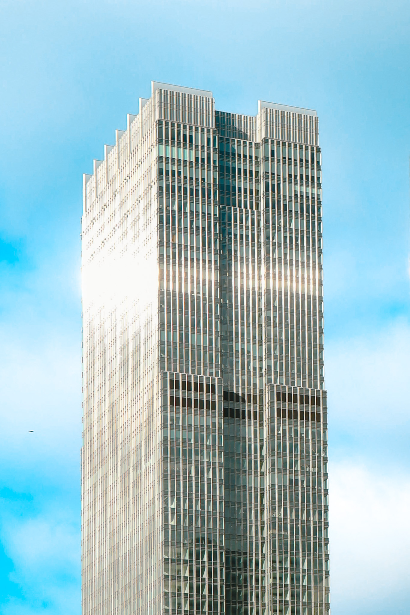 Tall modern skyscraper against a bright blue sky.