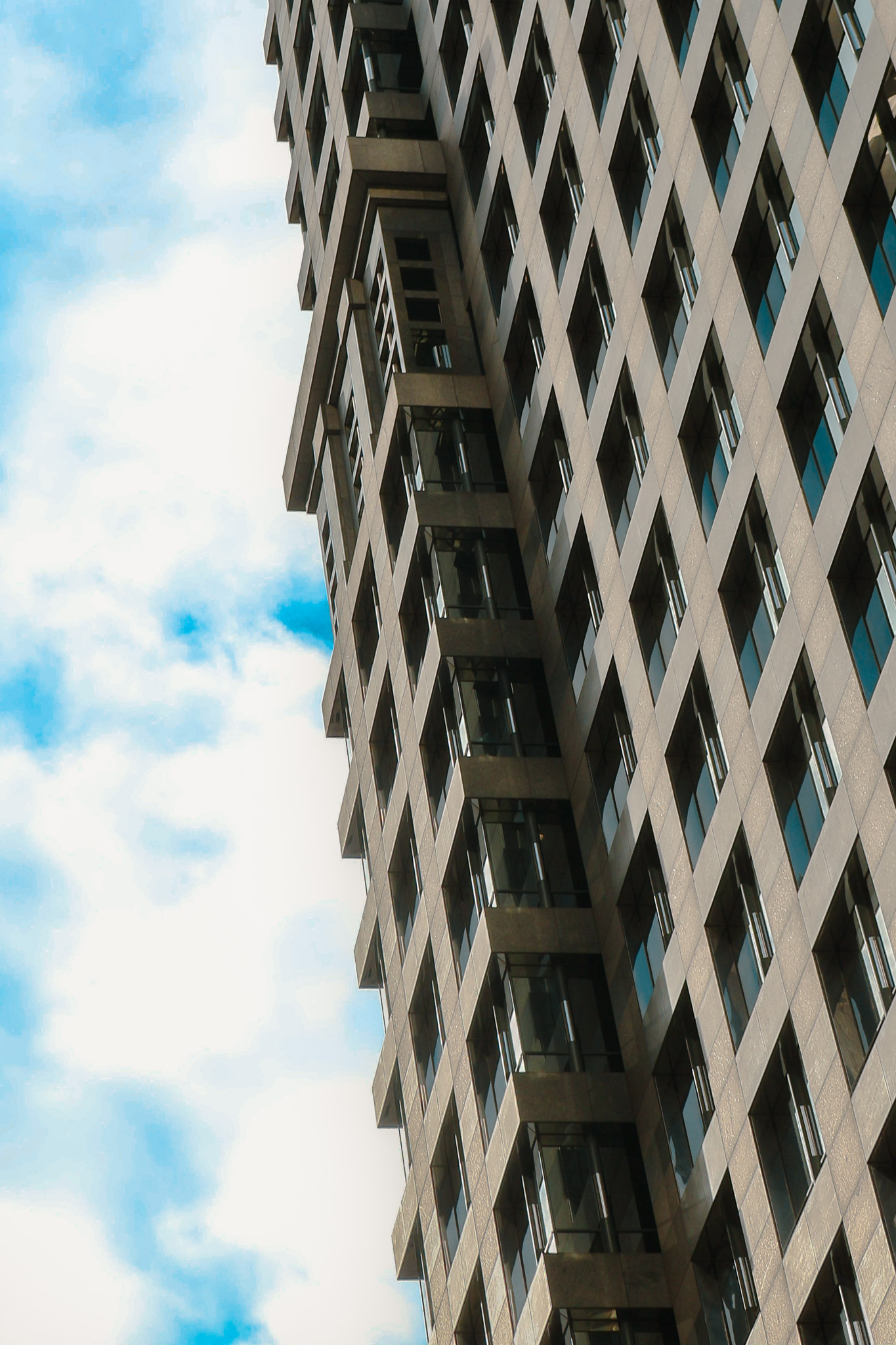 Upward-looking angle of a modern high-rise building with repeating window patterns.